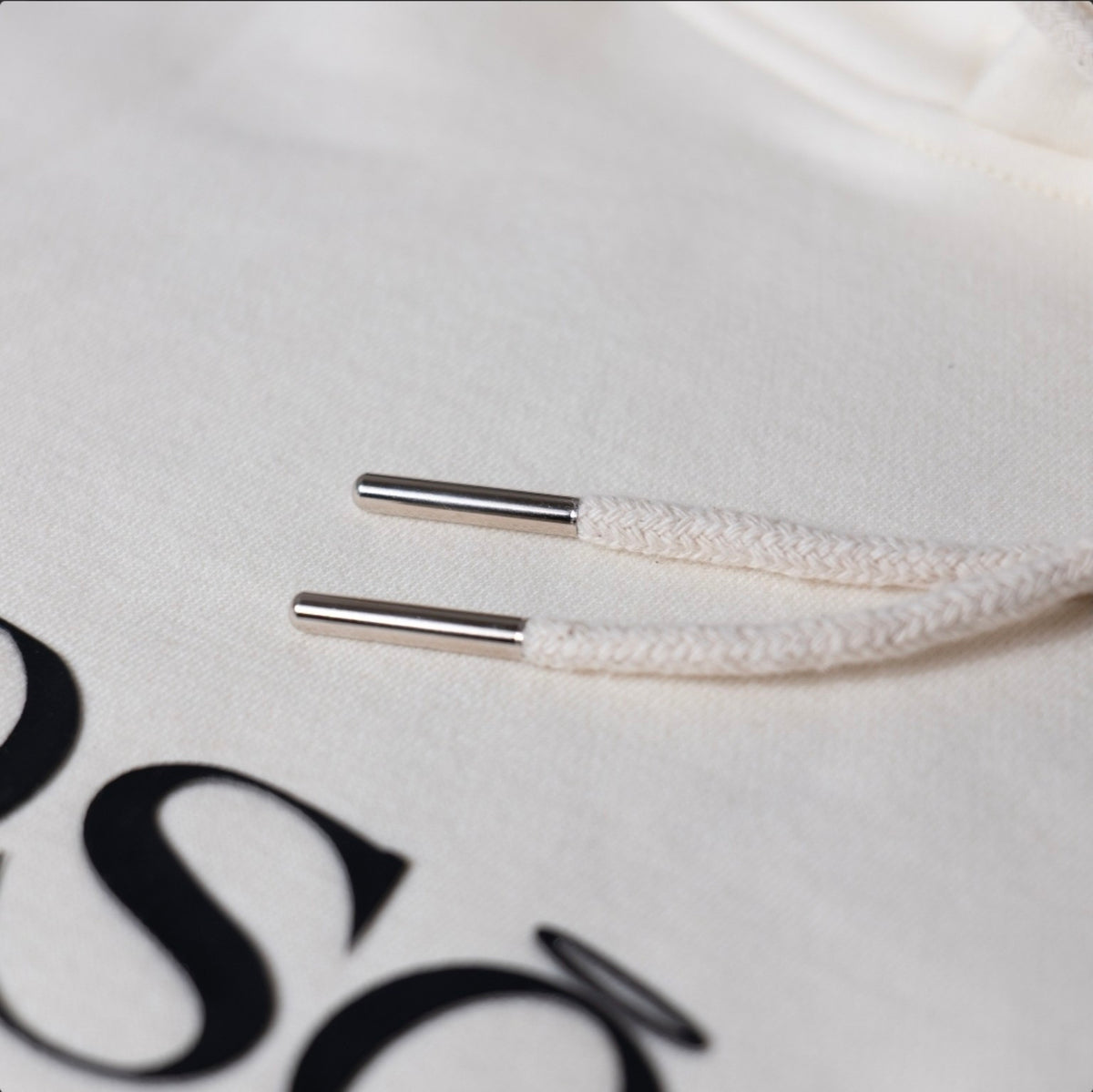 Close-up of the off-white braided drawcord with silver metal tips on the KiiNDSOULS heavyweight hoodie